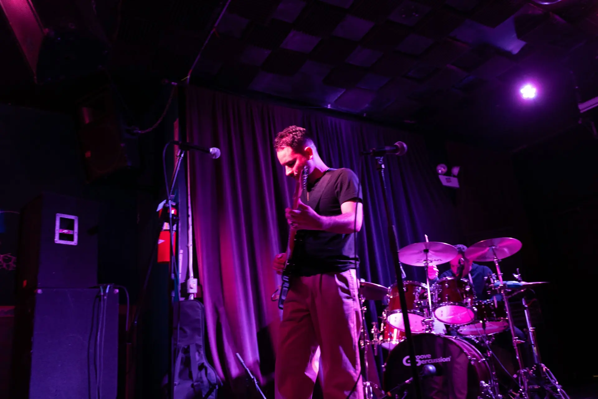 A man standing on a stage next to a drum set
