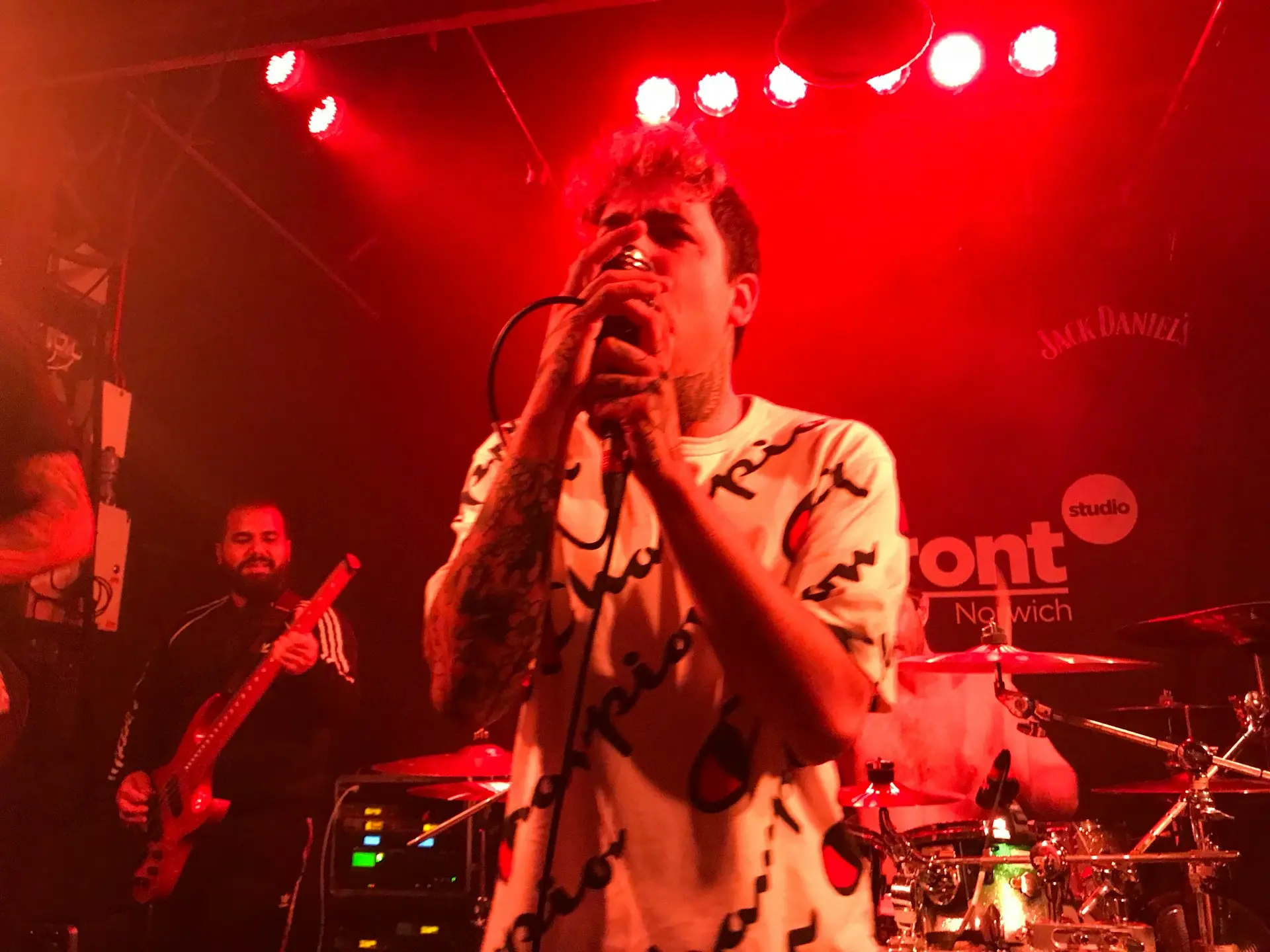 man singing holding microphone in front of man plying guitar in stage